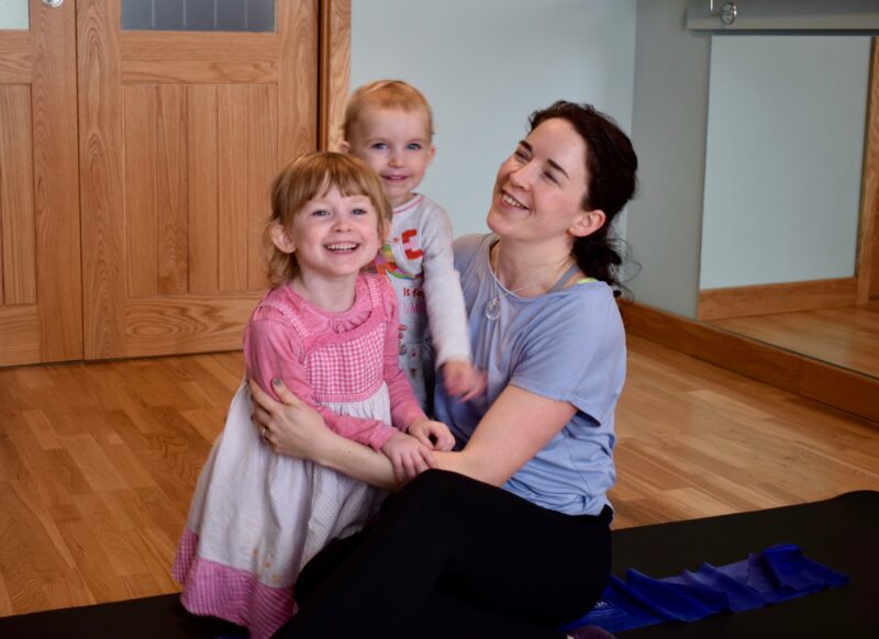 Family Pilates Emmeline Kemp a mother of two children sitting on the exercise mat smiling